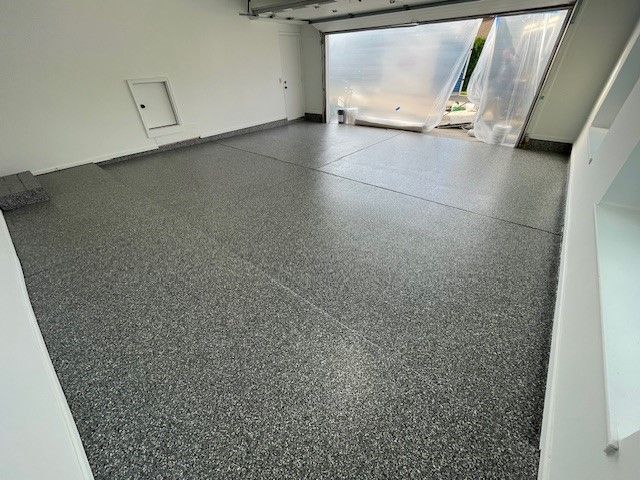 Gray epoxy garage floor with white walls and open garage door.
