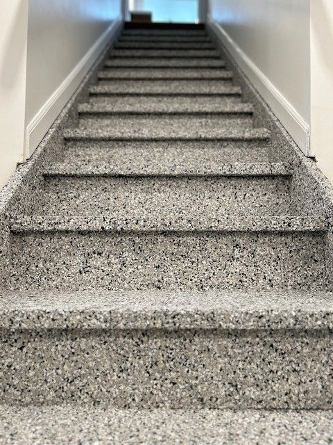 Staircase with speckled gray steps leading upward to a blurred light source.