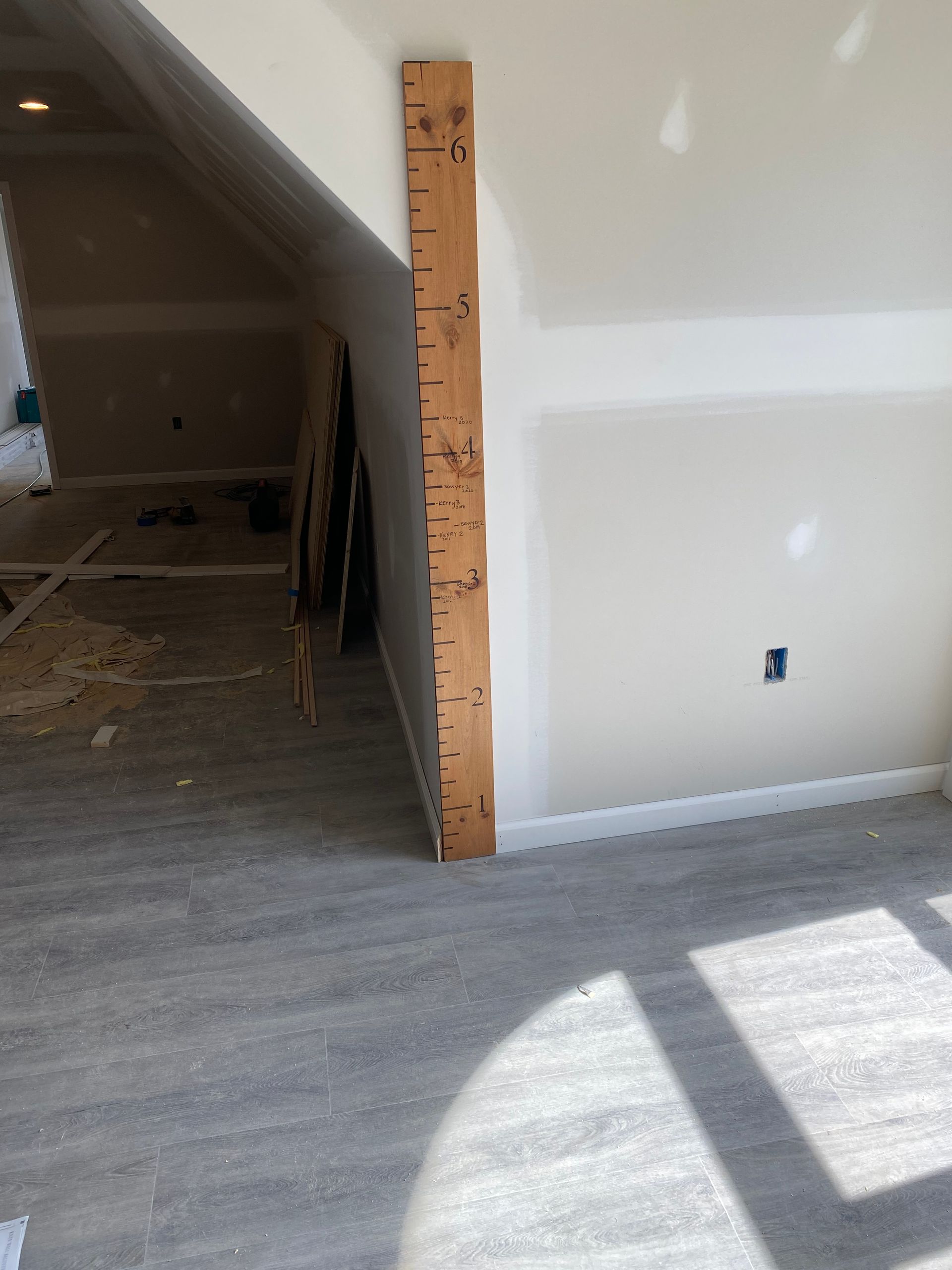Interior under construction with unfinished wall and doorway opening to a carpeted attic space