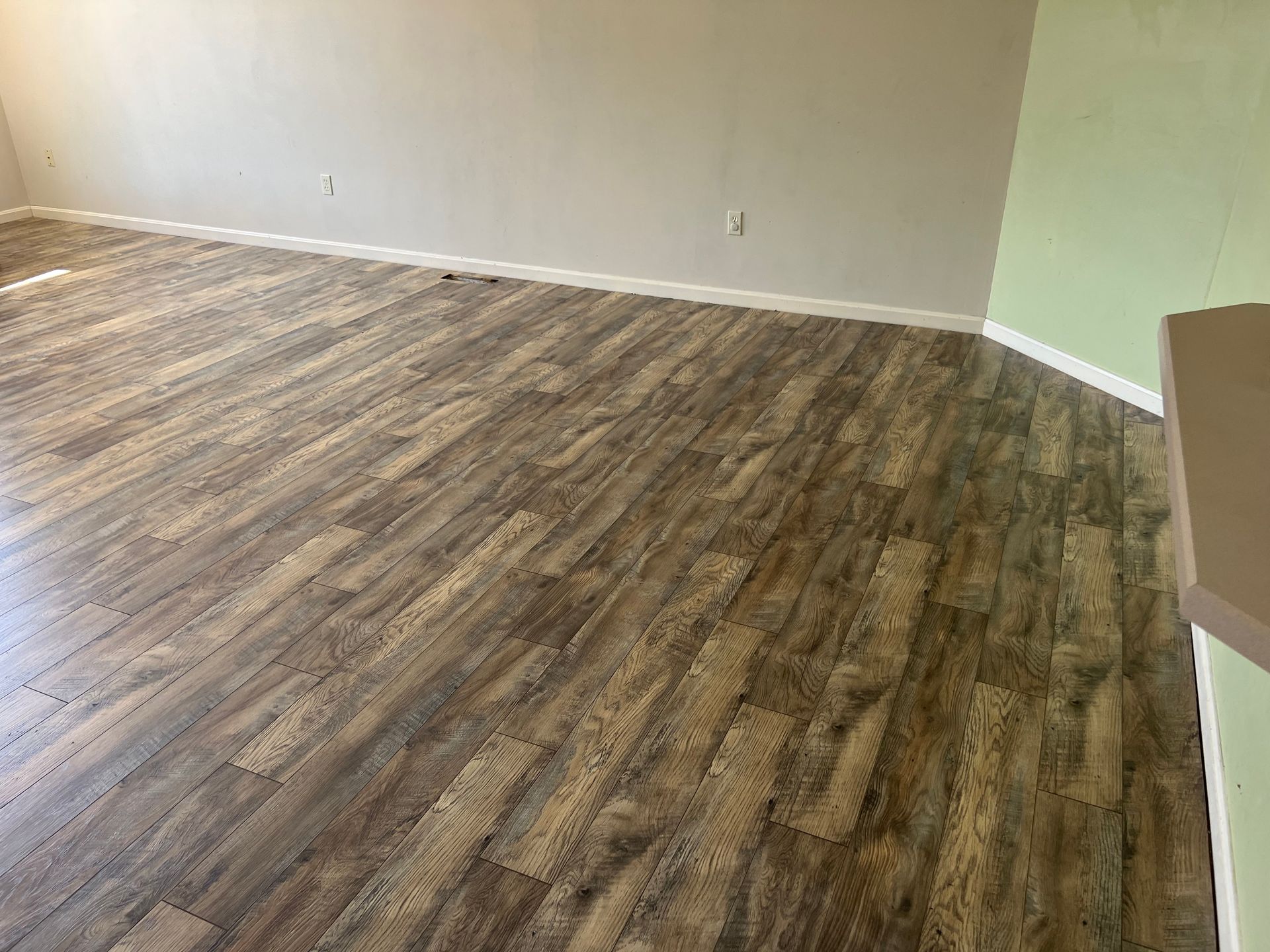 Empty room with wood-look flooring, beige walls, and white baseboards