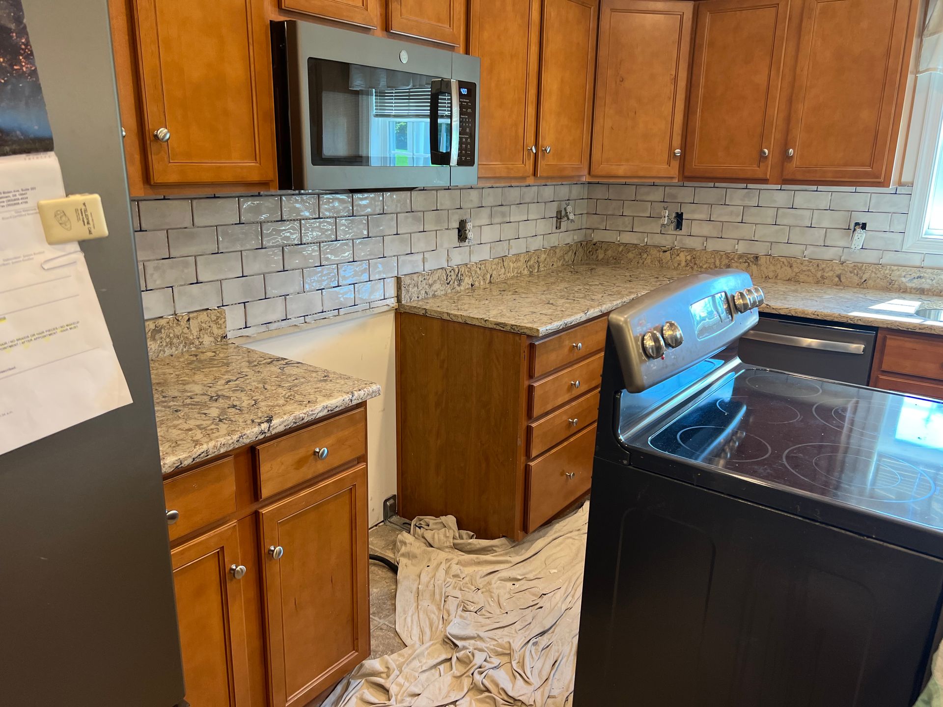 Kitchen with wood cabinets, granite countertops, tiled backsplash, and a stainless steel stove beneath a microwave.