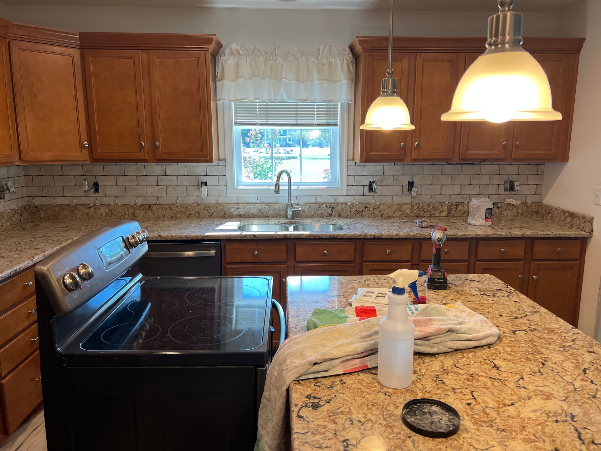 Bright kitchen with wood cabinets, granite counters, black stove, and a window over the sink.