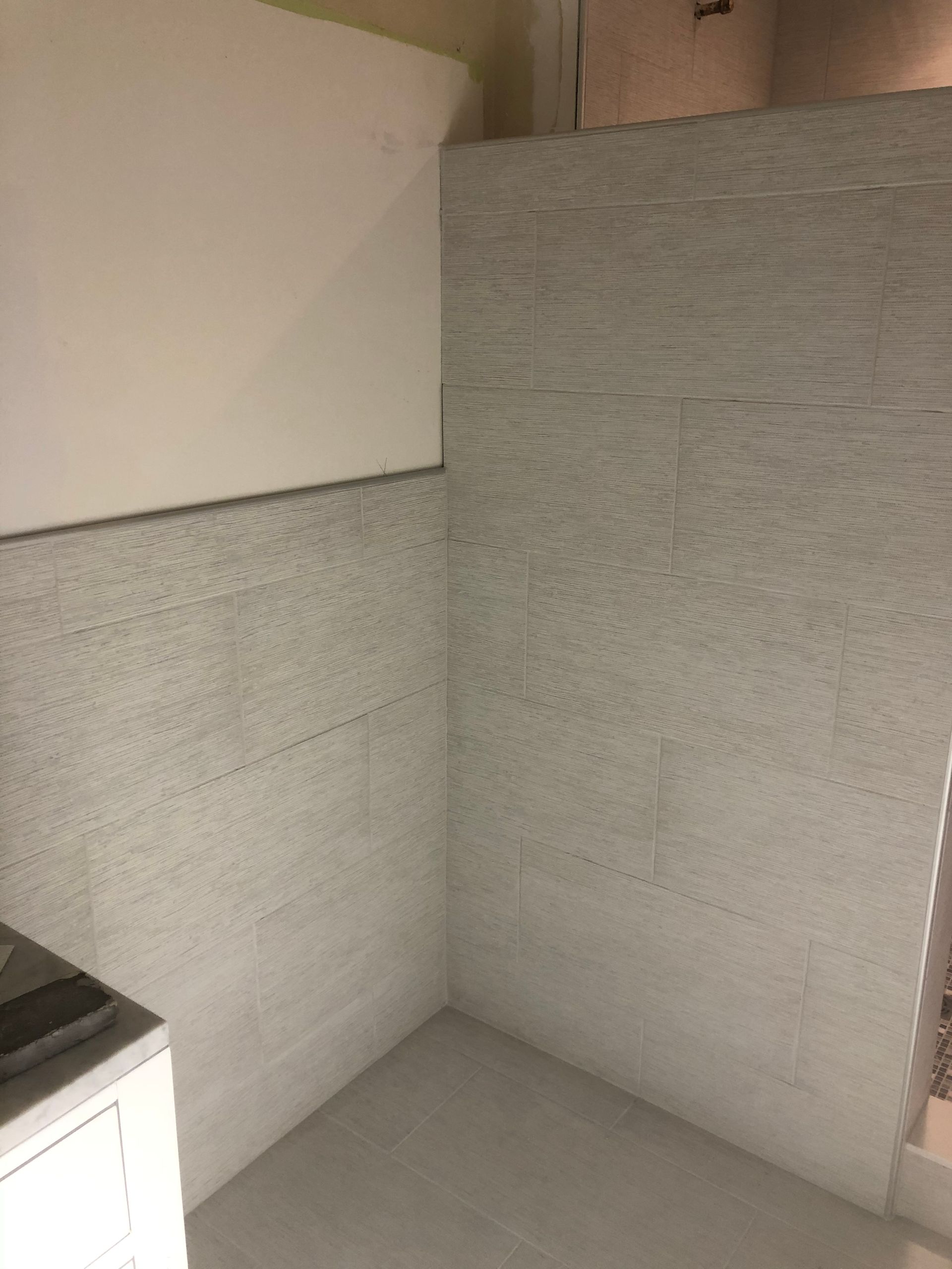 Empty gray corner of a room with a countertop at left and a white cabinet below.
