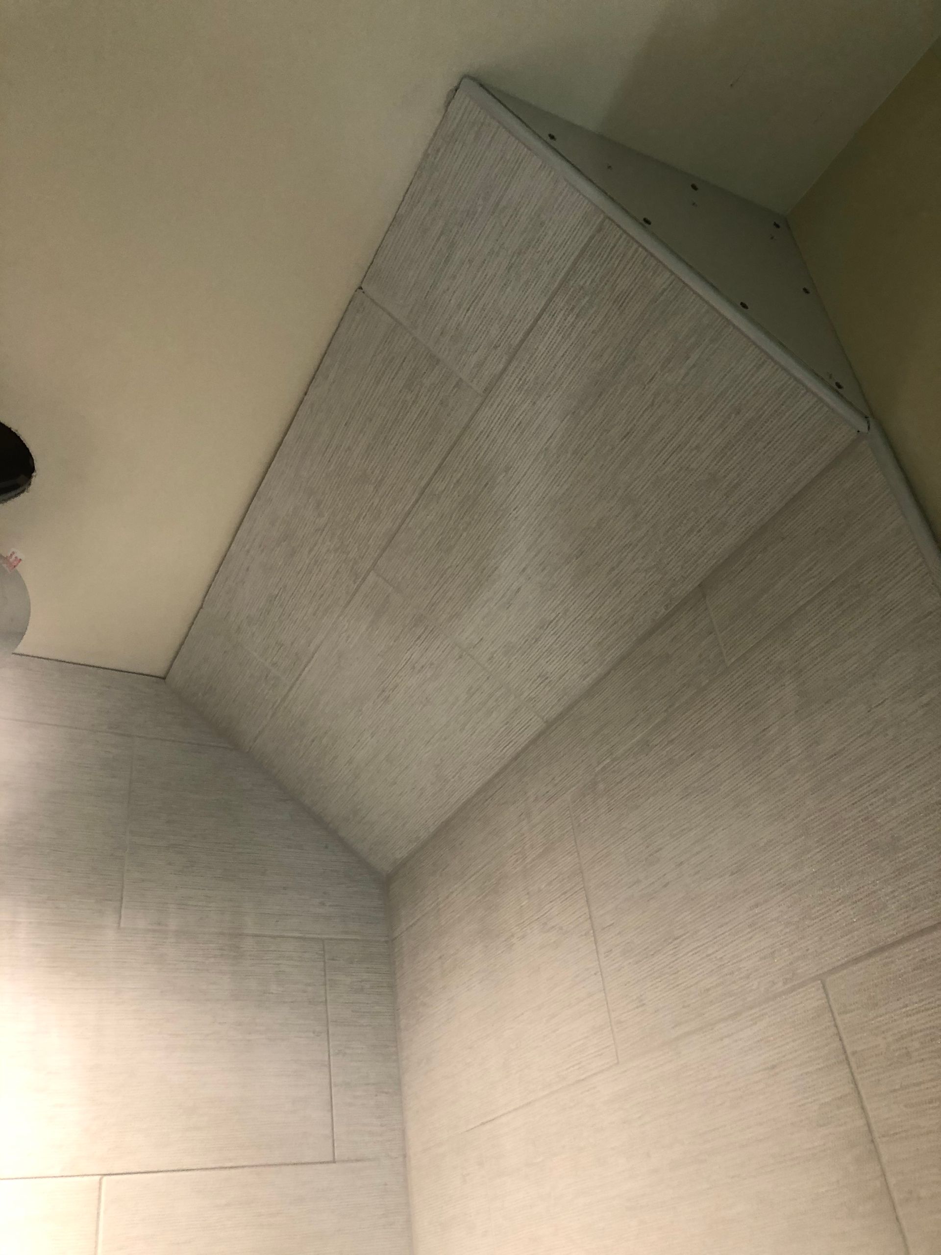 Gray fabric-lined ceiling panels meeting in a corner, with a small vent near the top.