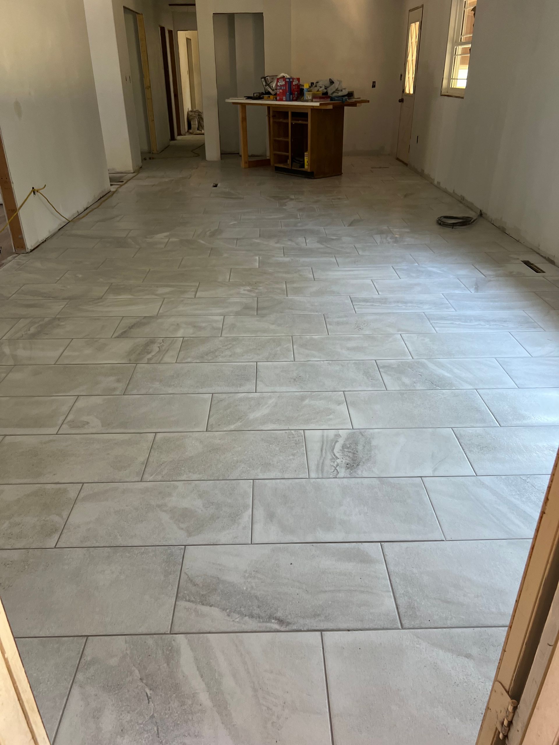 Unfinished room with tiled floor, bare walls, and a table at the far end.