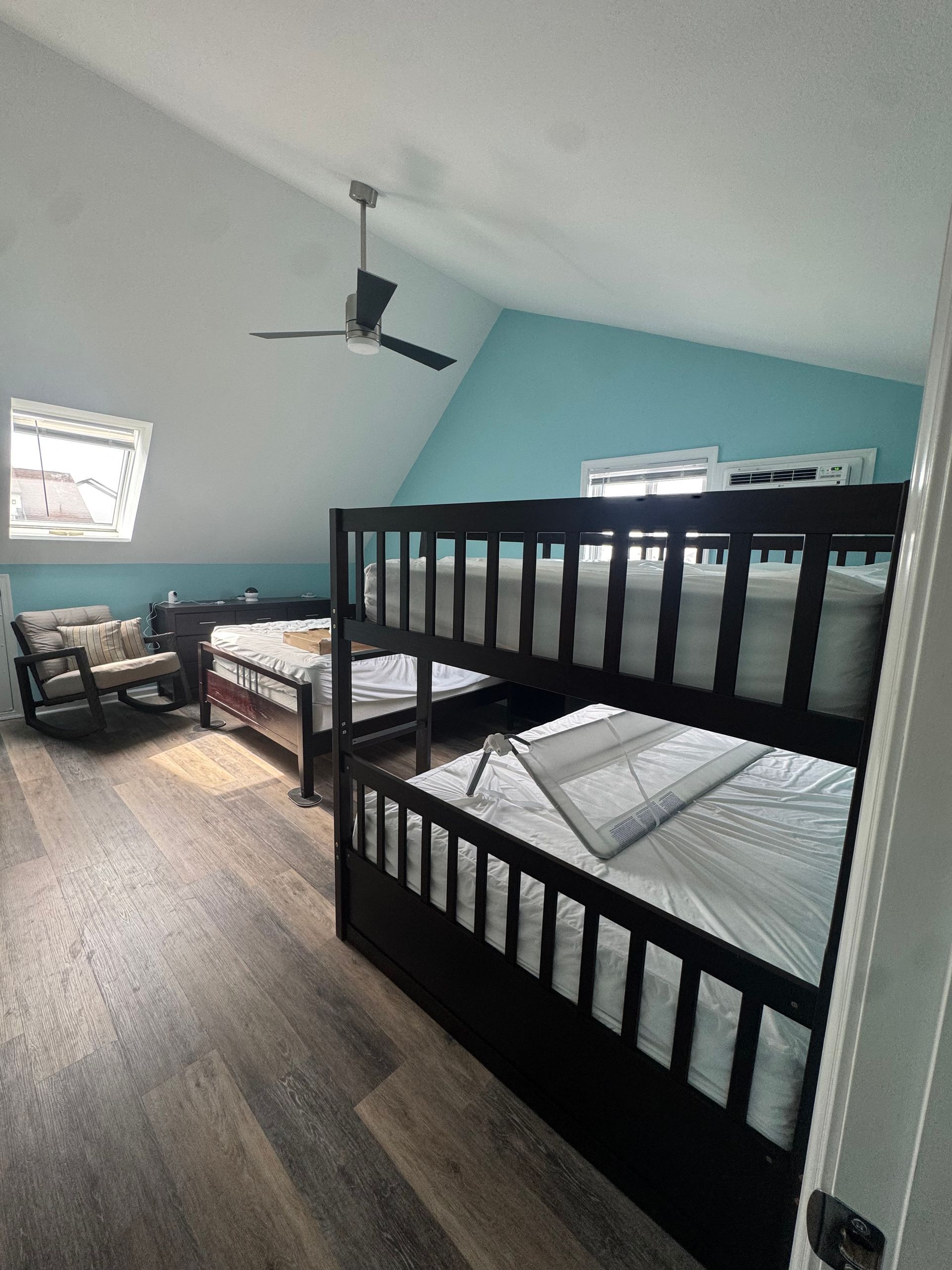 Bedroom with bunk bed, twin bed, and ceiling fan in a light blue room