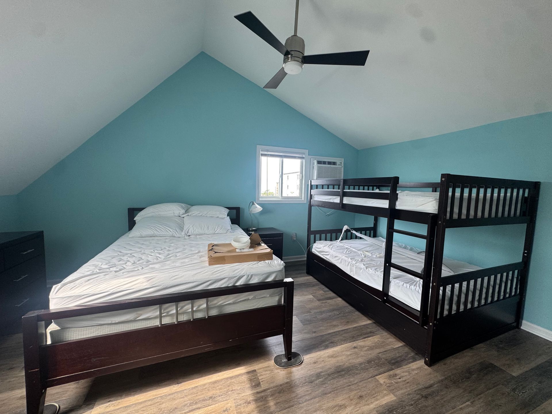 Blue bedroom with a bed, bunk beds, sloped ceiling, ceiling fan, and small window