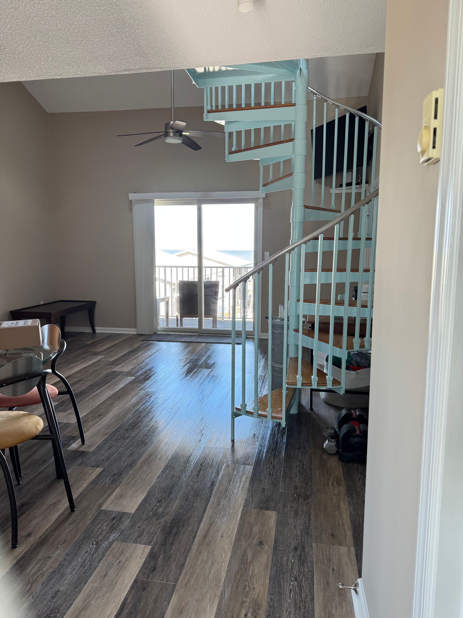 Living room with spiral staircase, tall windows, and hardwood floors