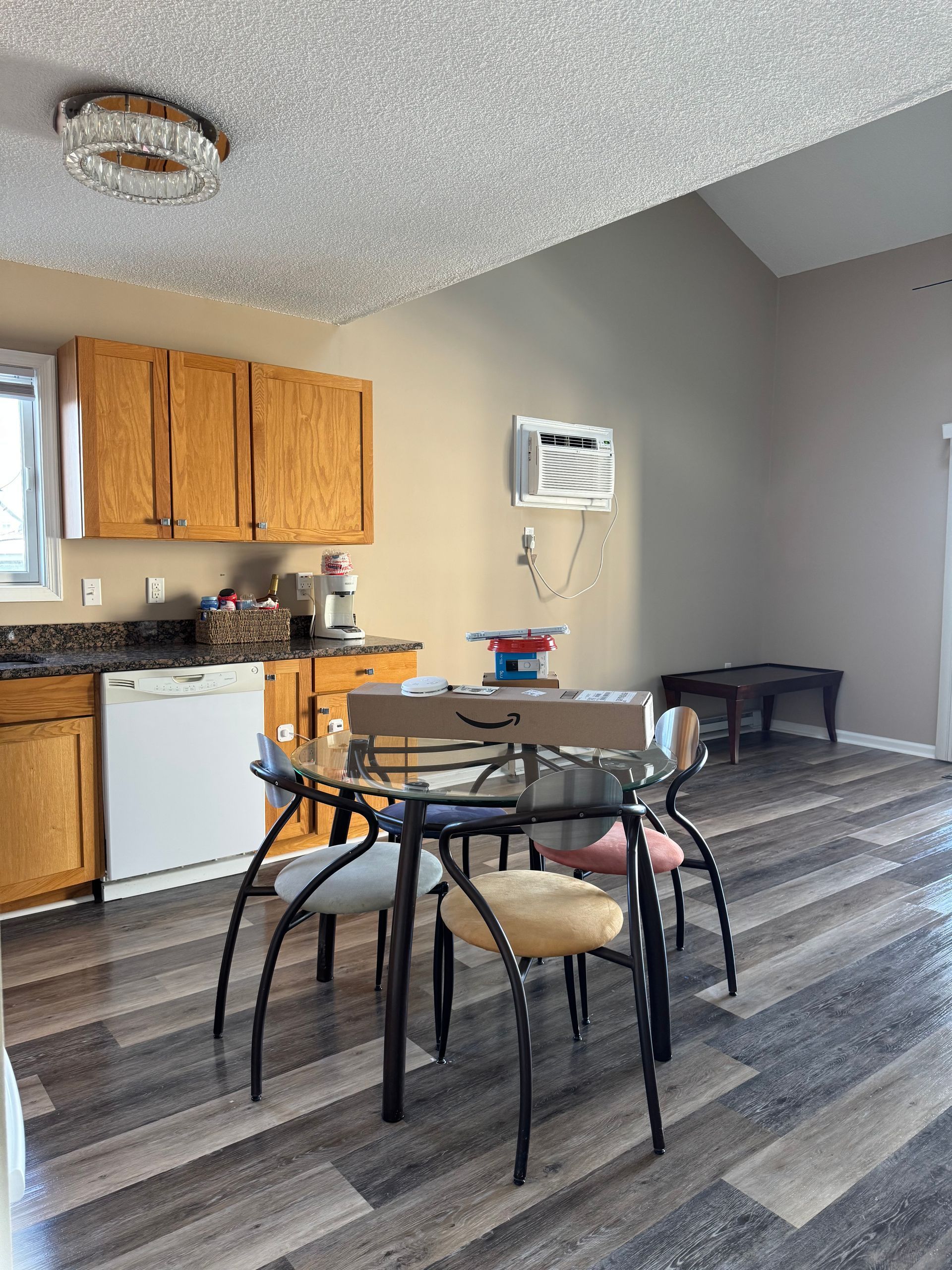 Small kitchen and dining area with wood cabinets, round table, and gray flooring.