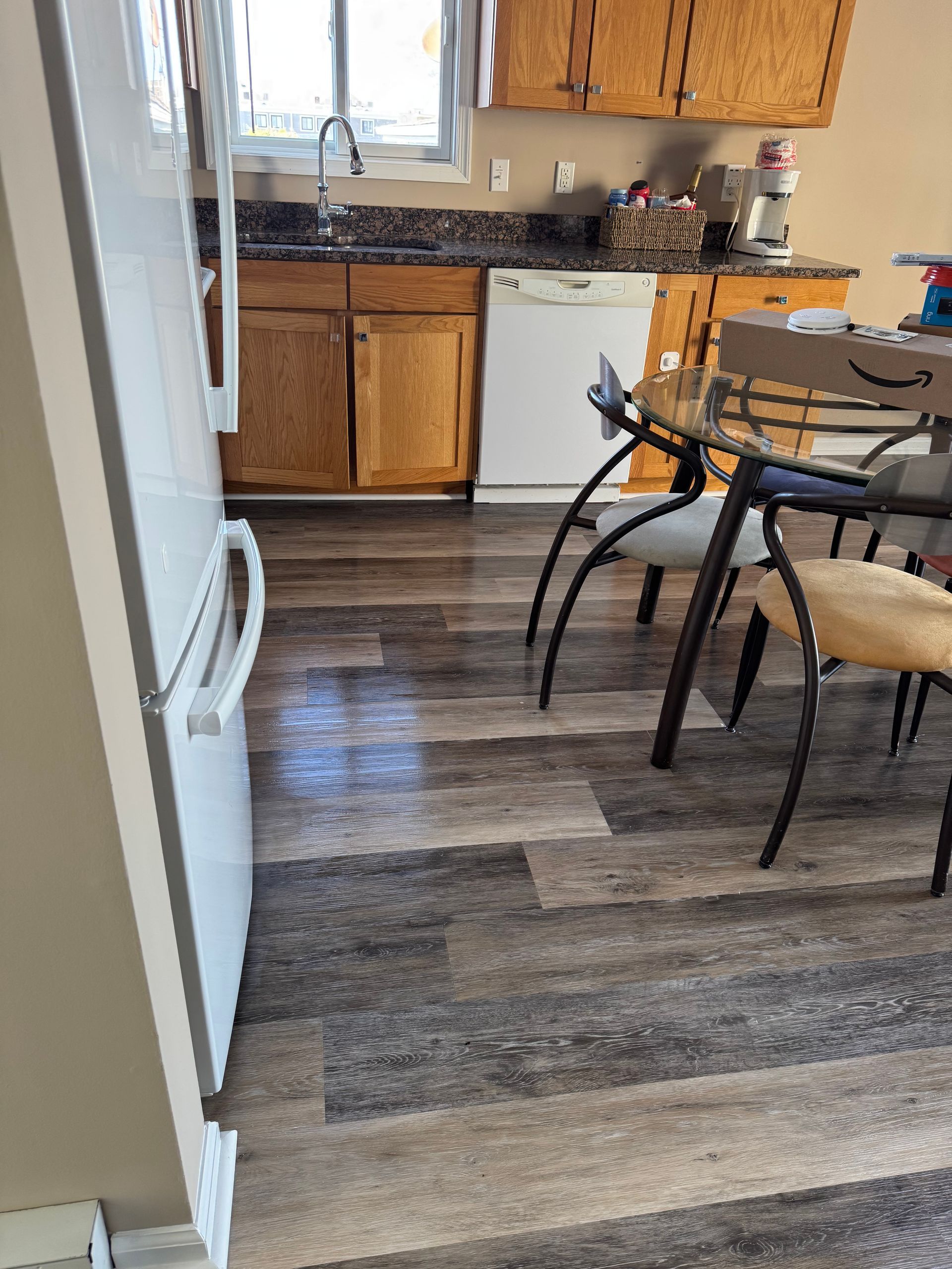 Kitchen with wood cabinets, white appliances, and a dining table on dark wood flooring.