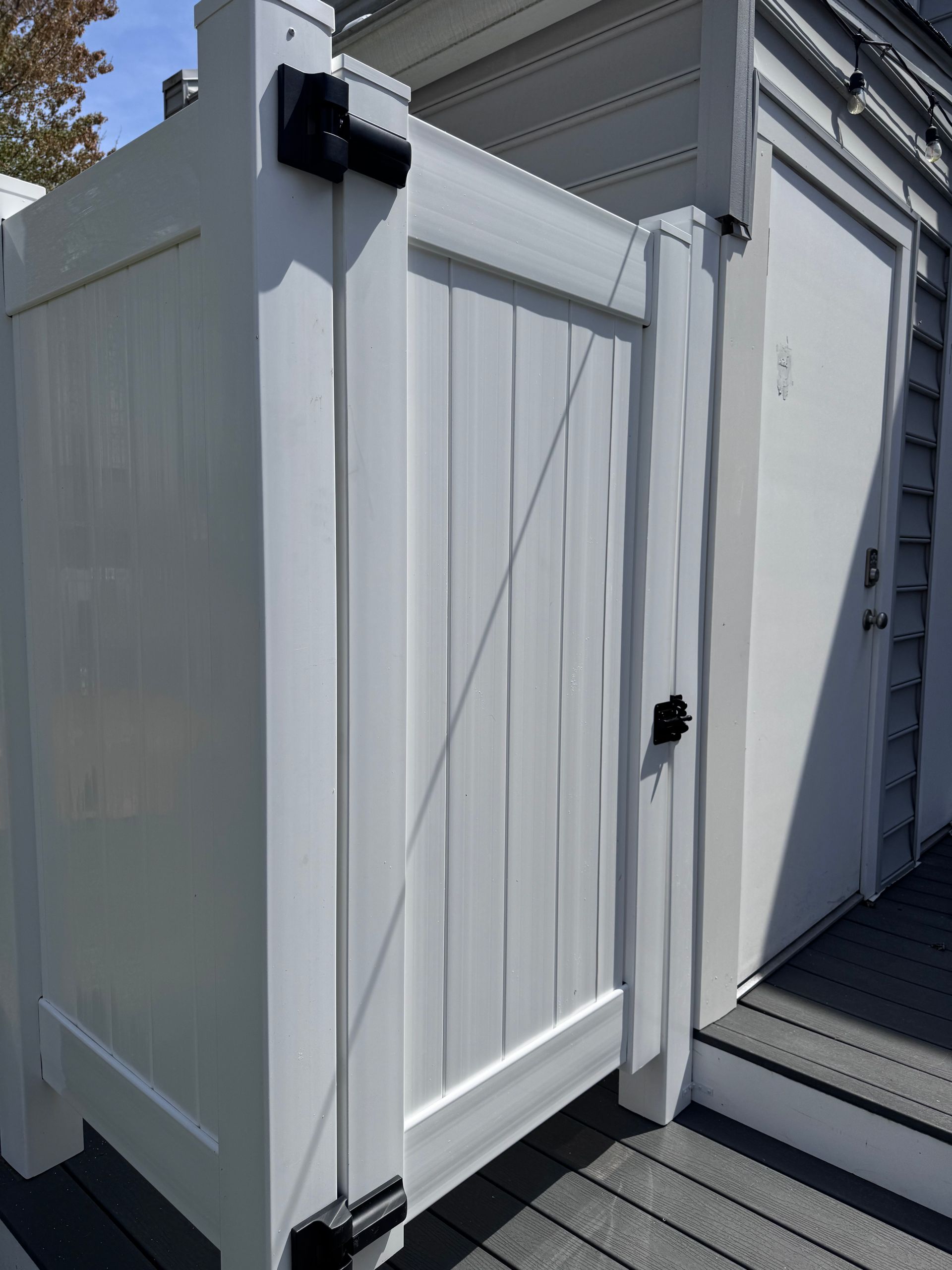 White outdoor utility cabinet with closed double doors and black hardware beside a building stairway