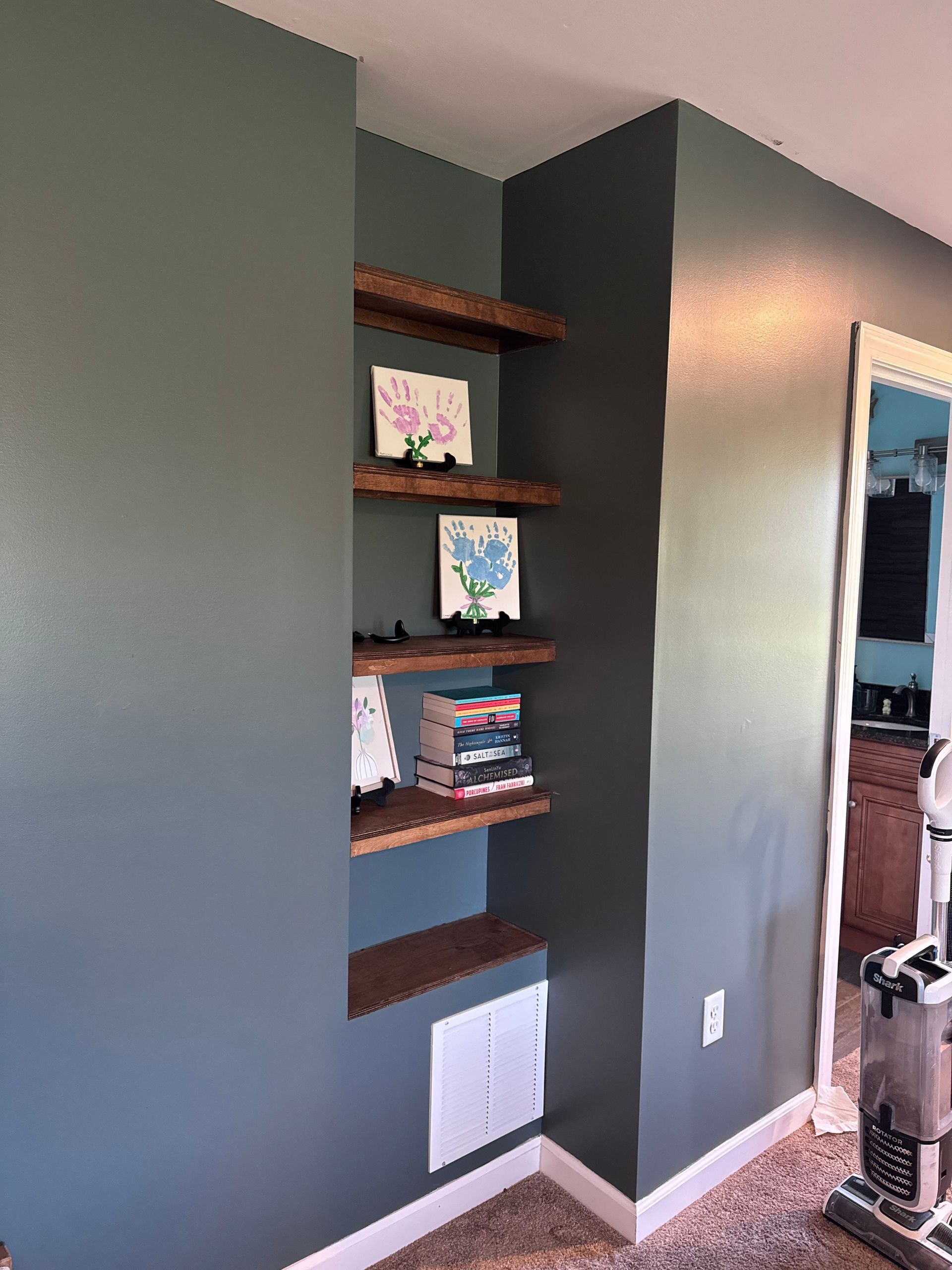 Built-in wall shelves with books and framed art in a gray hallway niche