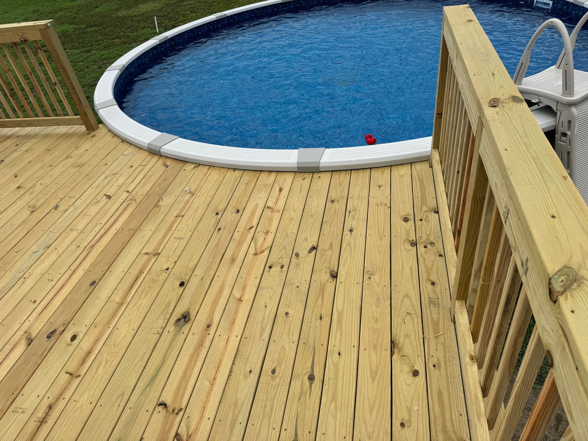 Wooden pool deck beside a round blue swimming pool with white edging.