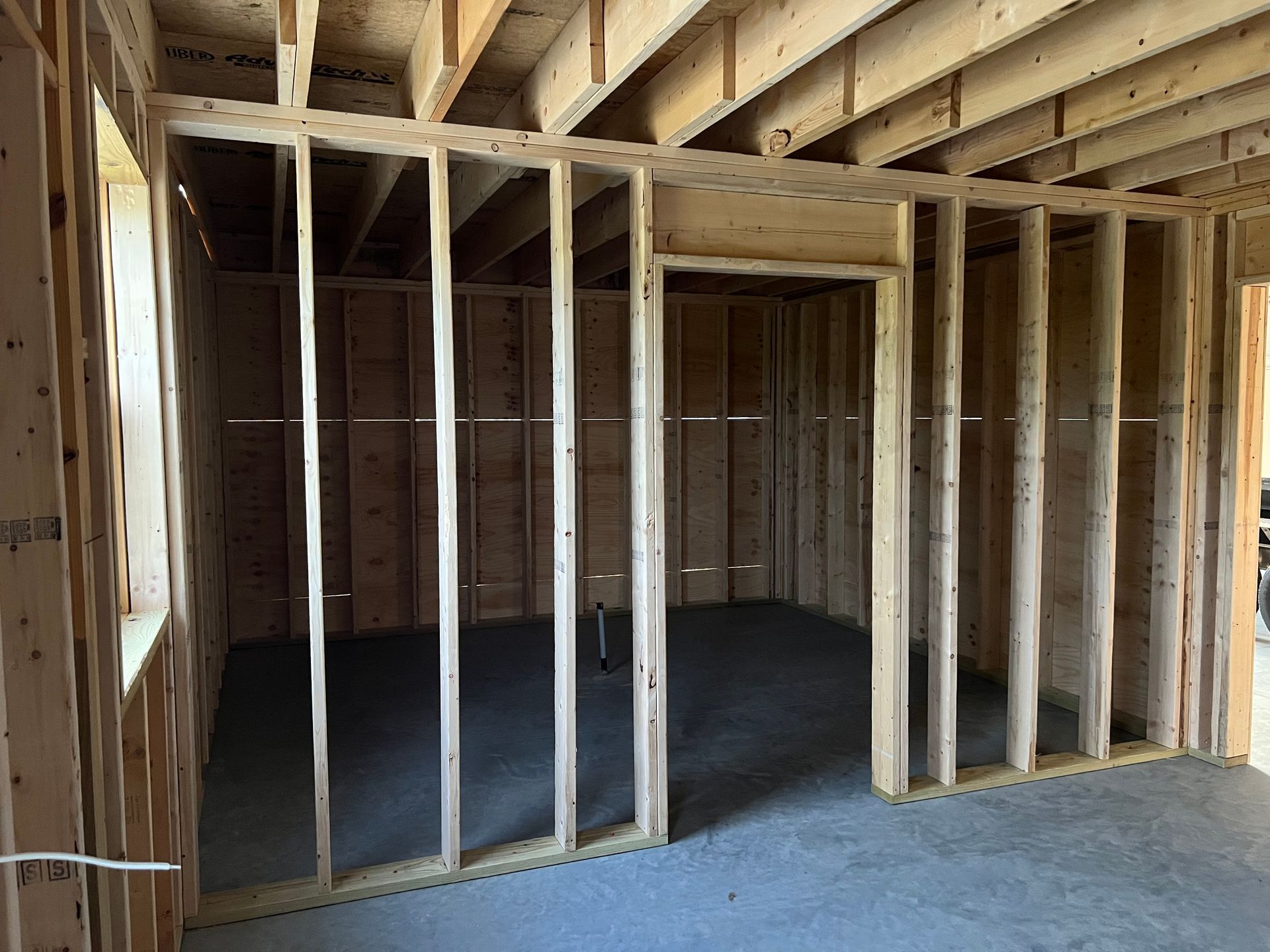 Interior of a framed house under construction, with exposed wood studs and subflooring.