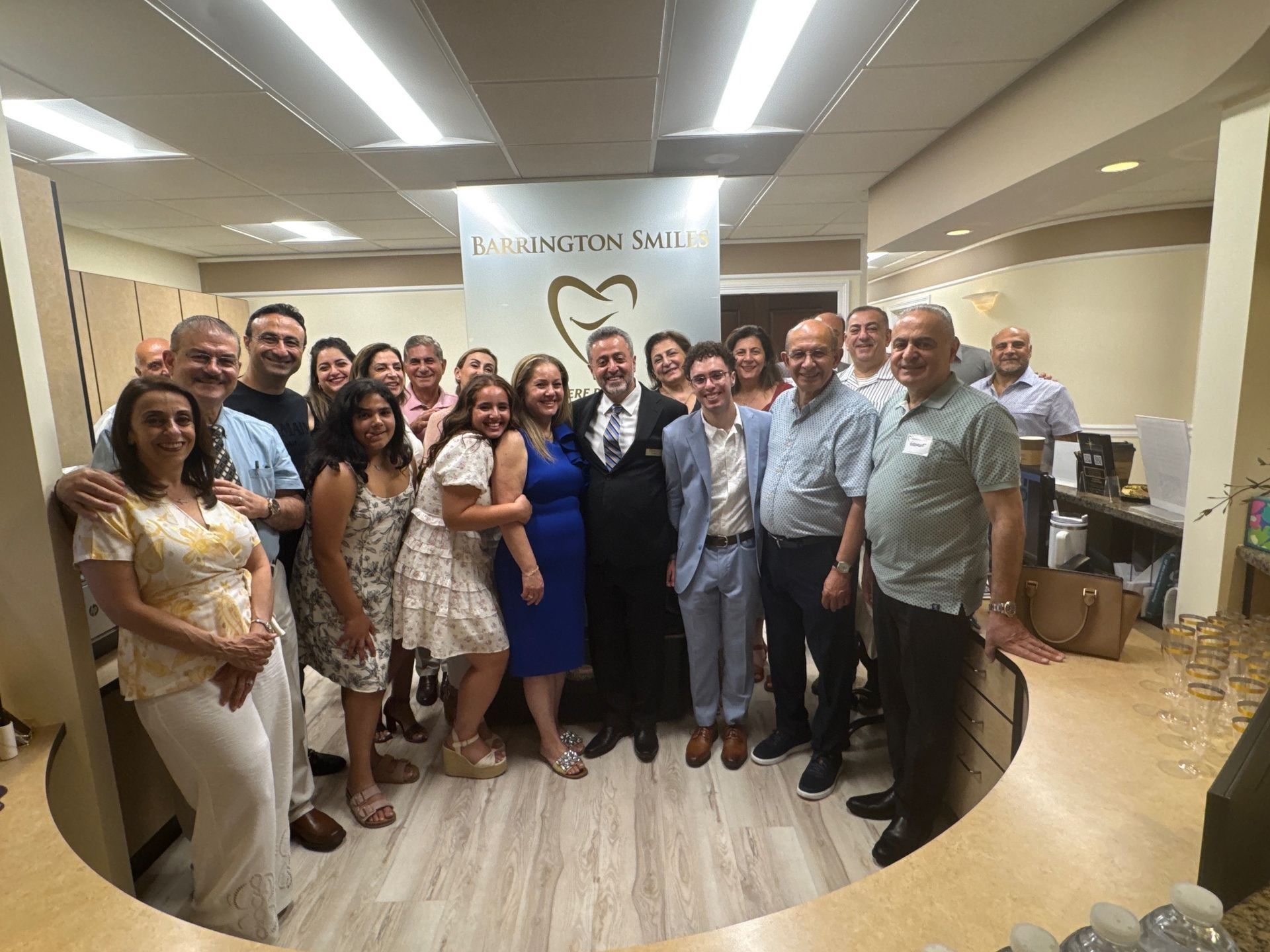 Group of people inside a dental office, posing for a photo. A sign above them reads 