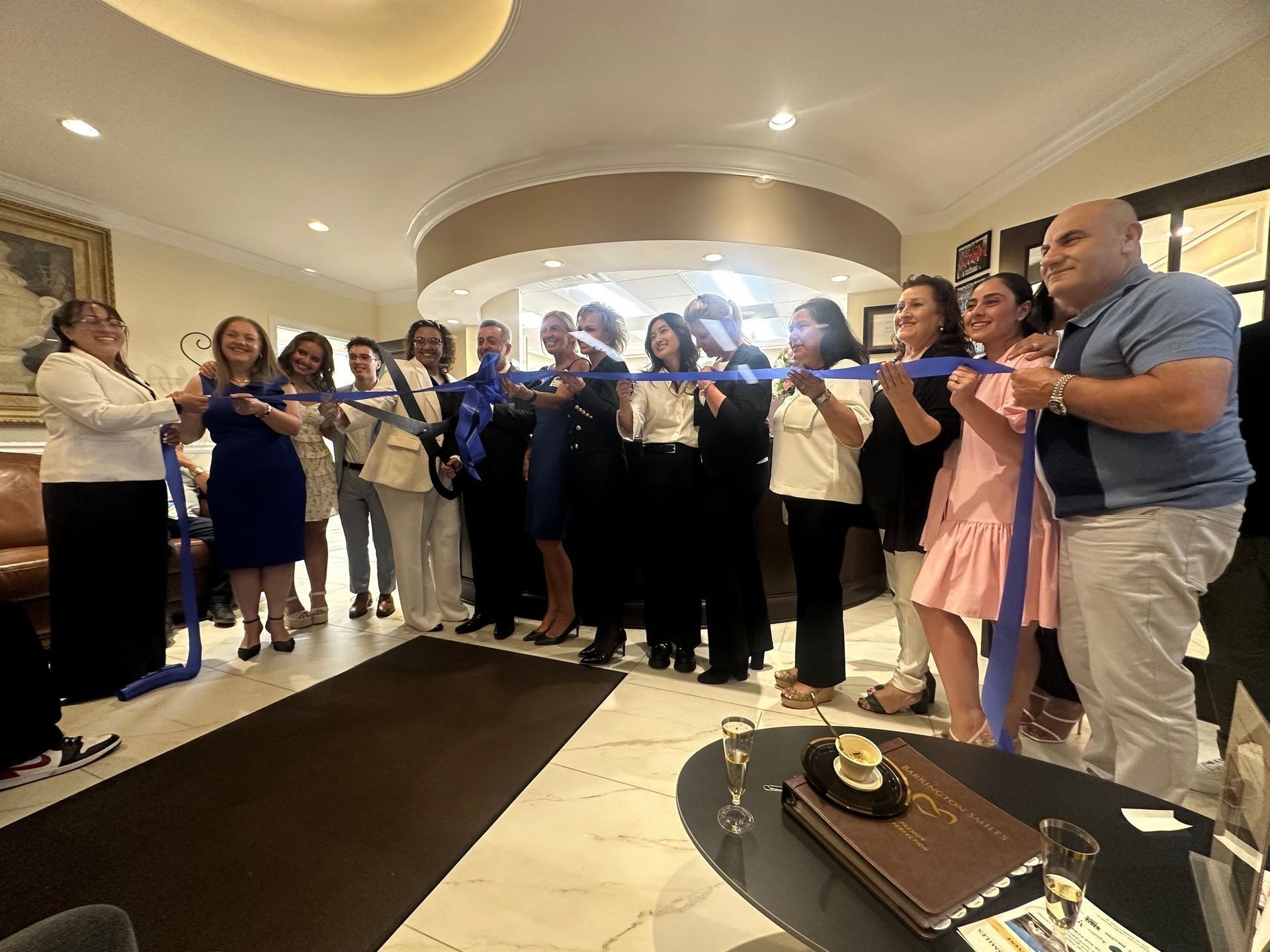 People cutting a blue ribbon at a grand opening in a stylish interior.
