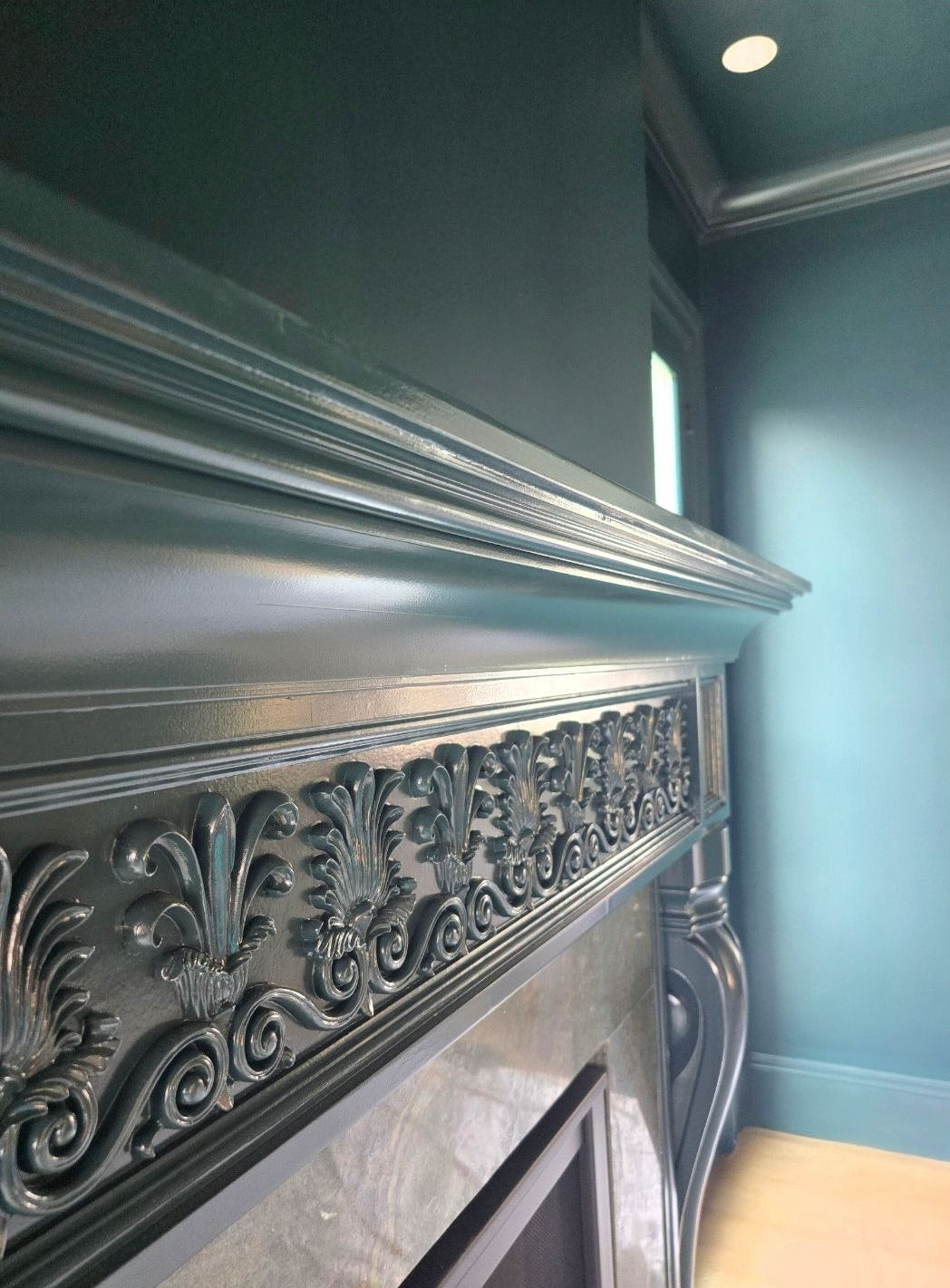 Green ornate fireplace mantel with decorative carvings.