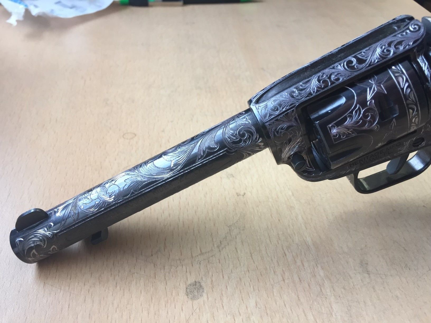 Ornately engraved revolver on a wooden surface.