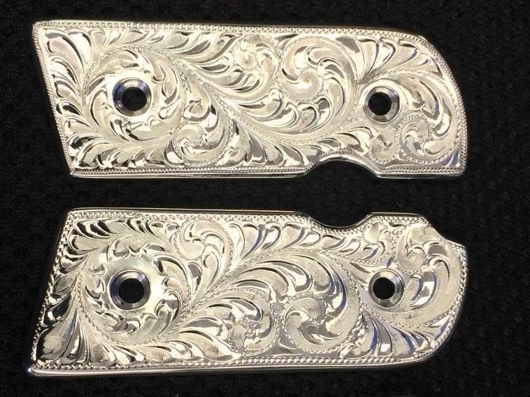 Engraved silver gun grips, floral scroll design, two pieces with screw holes.