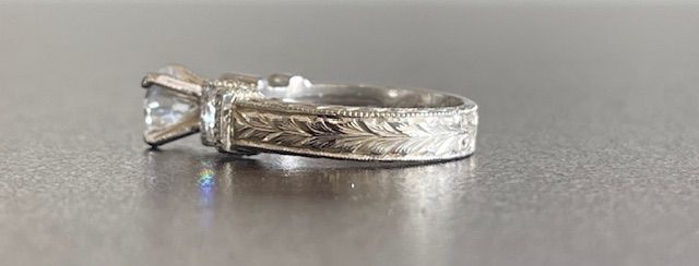 Silver ring with engraved band and a large, clear gemstone.