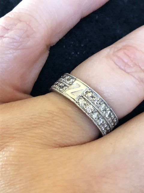 Close-up of a silver ring with diamonds and the letter 