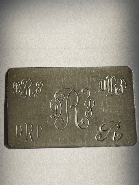 Engraved metal plate with ornate letter 