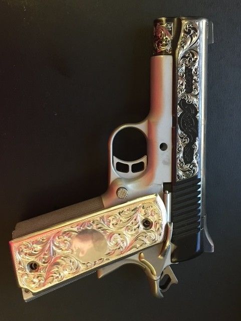 Silver and black handgun with ornate engraved floral design.