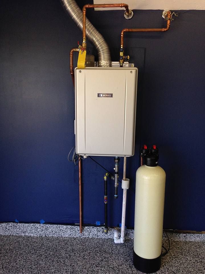A white water heater is mounted to a blue wall