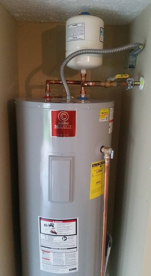 A water heater is sitting in a corner of a room.