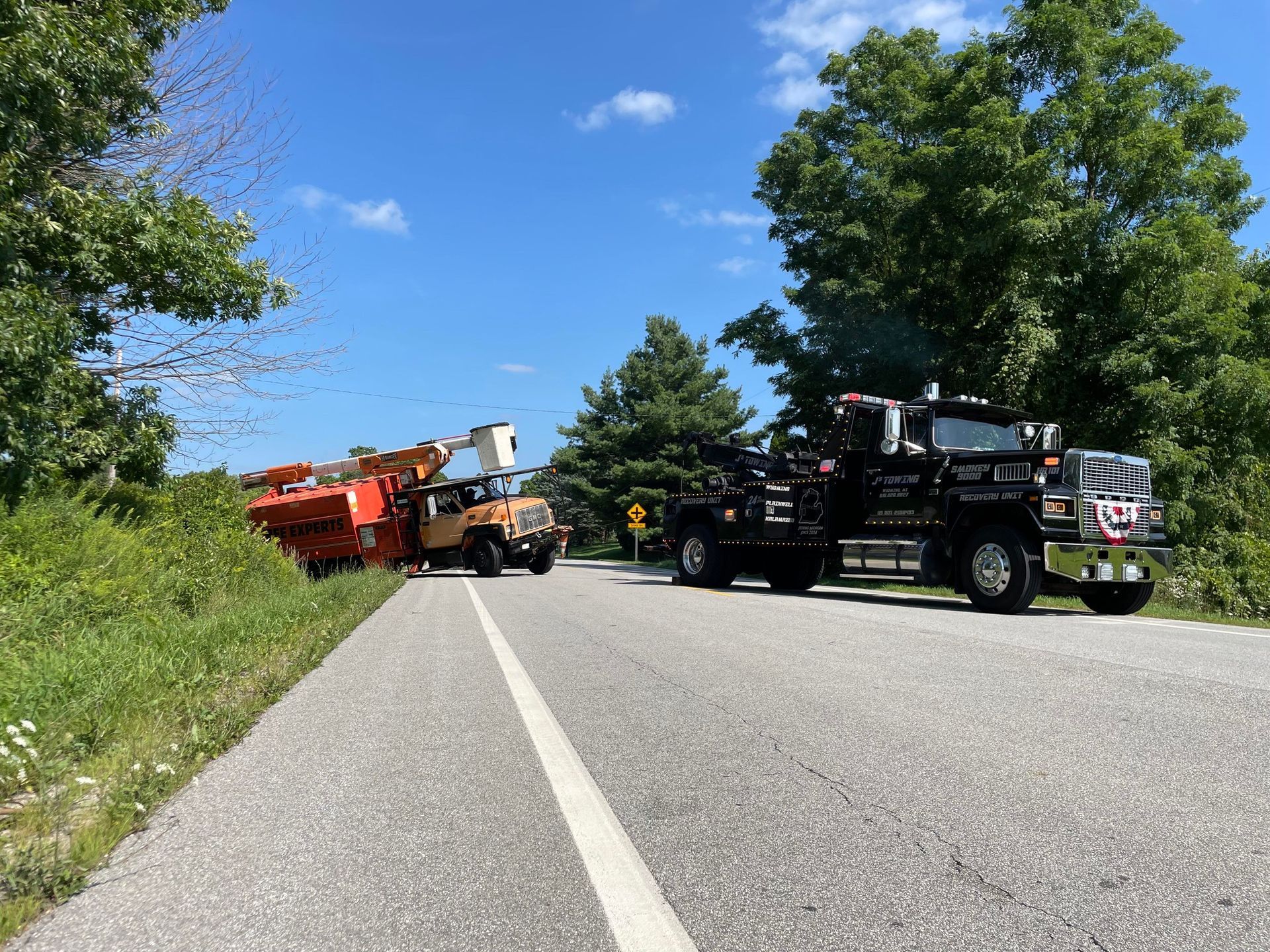 Two tow trucks are parked on the side of a road.