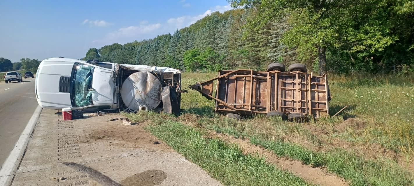 A white van has rolled over on the side of the road.