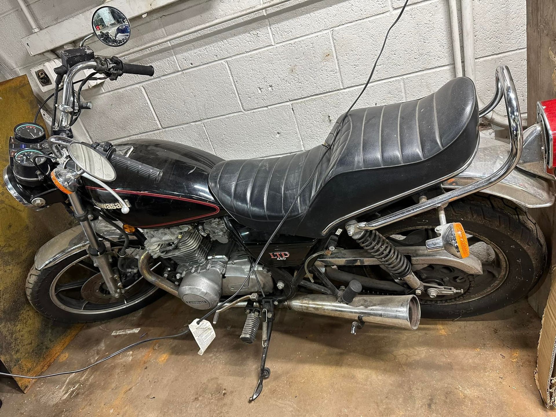 A black motorcycle is parked in a garage next to a brick wall.