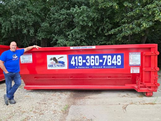 Man standing beside a red dumpster with 419-360-7848 and a logo on the side.