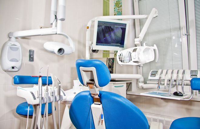 Modern dental clinic with blue chairs, dental tools, and monitor screens