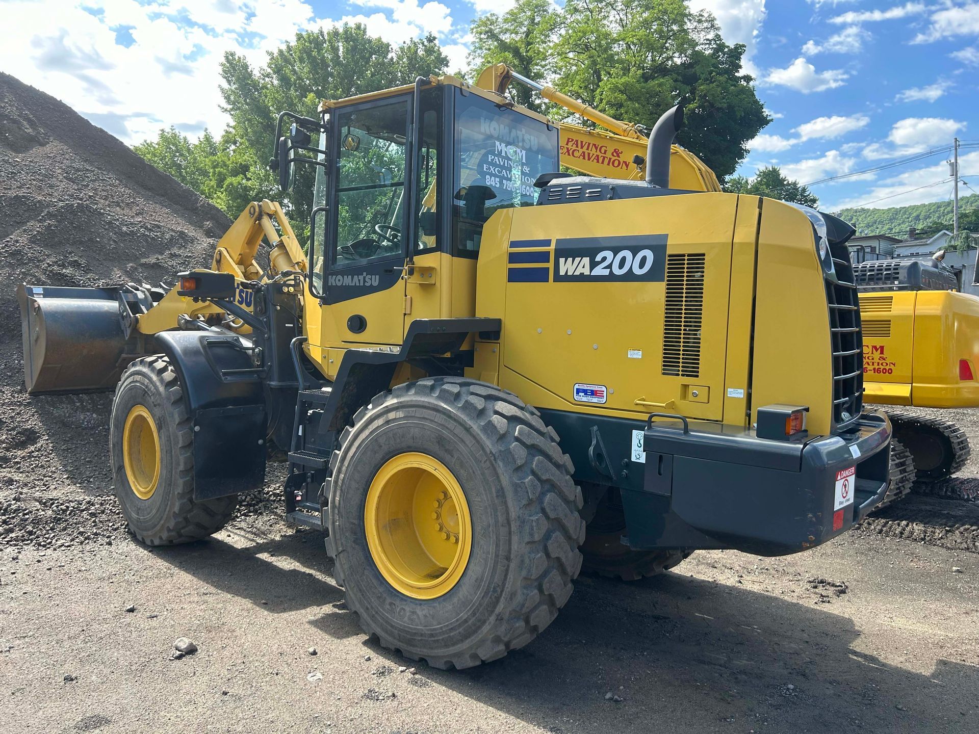 A yellow wheel loader is parked in front of a pile of dirt.