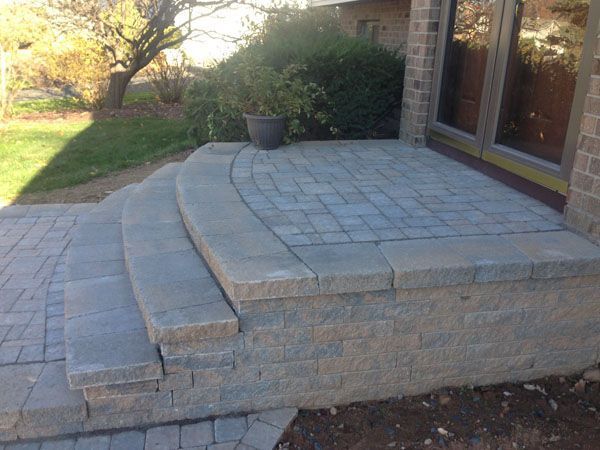 A brick porch with steps leading up to it and a brick wall.