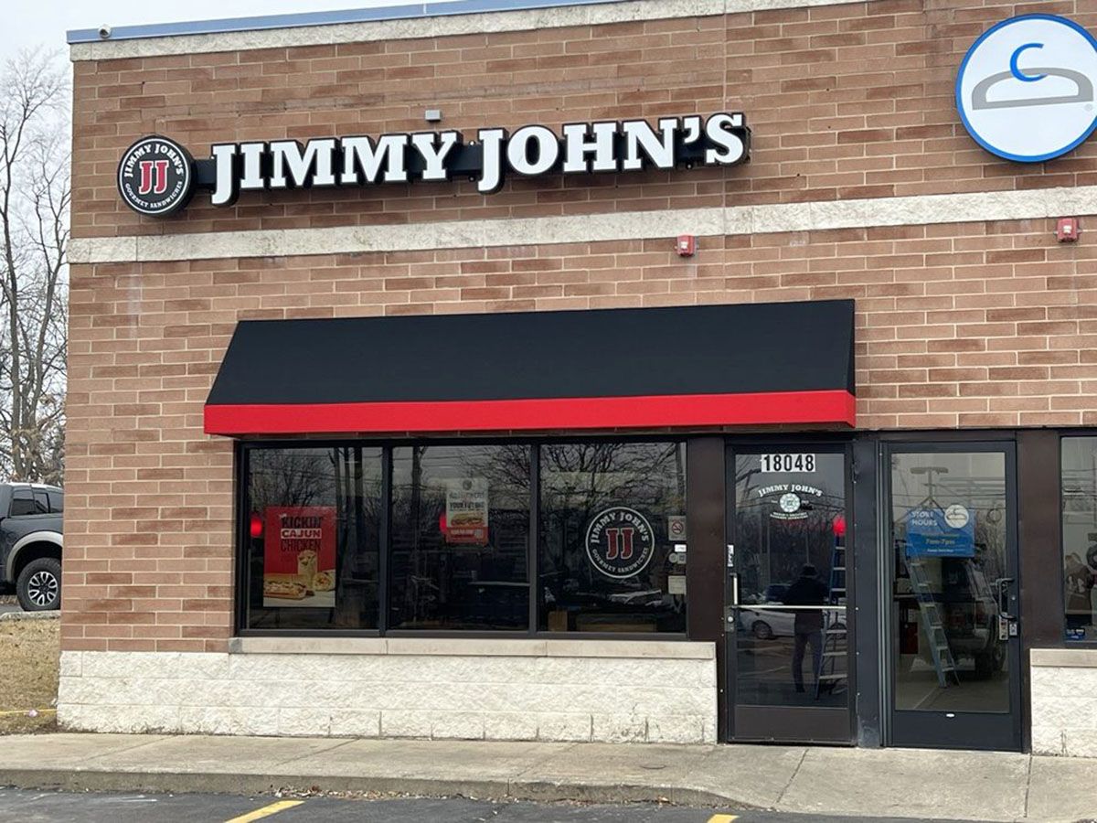 A storefront with black awning, brick facade, and glass door