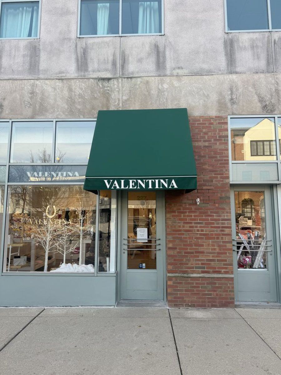 A boutique with green awning, glass storefront, and brickwork