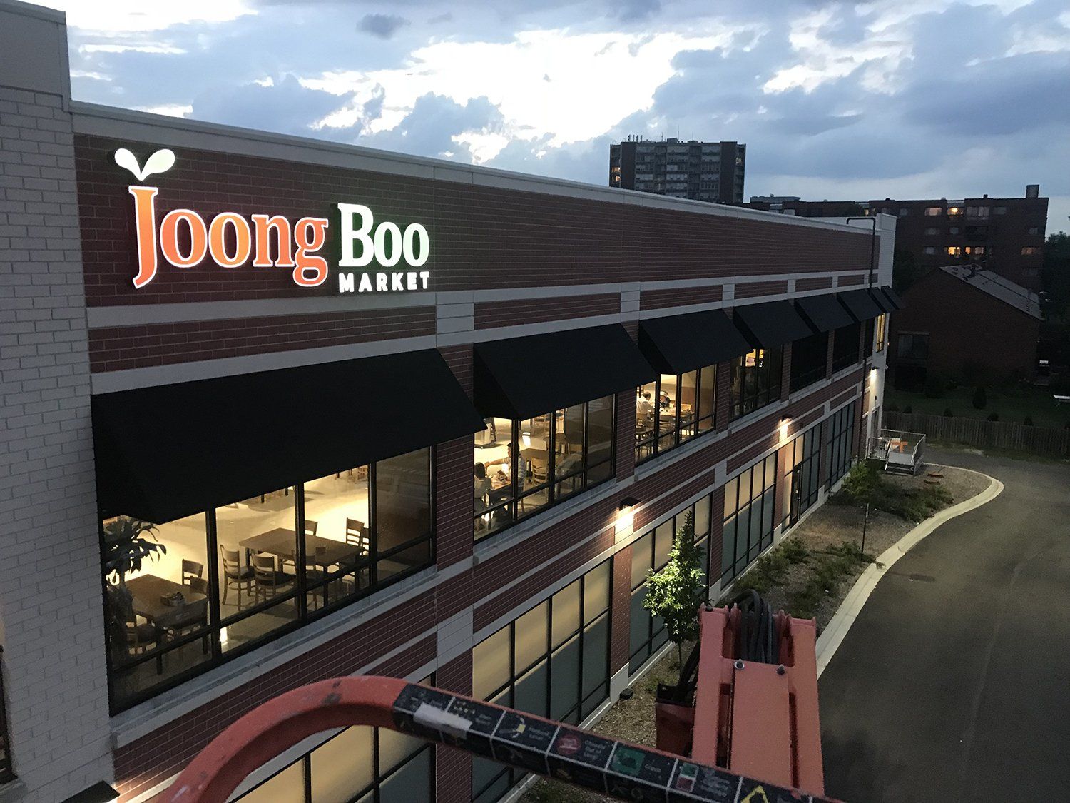 A building exterior with illuminated sign, brick facade, and awnings