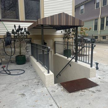 Entrance to a basement with metal railings, a canopy, and a stairwell.
