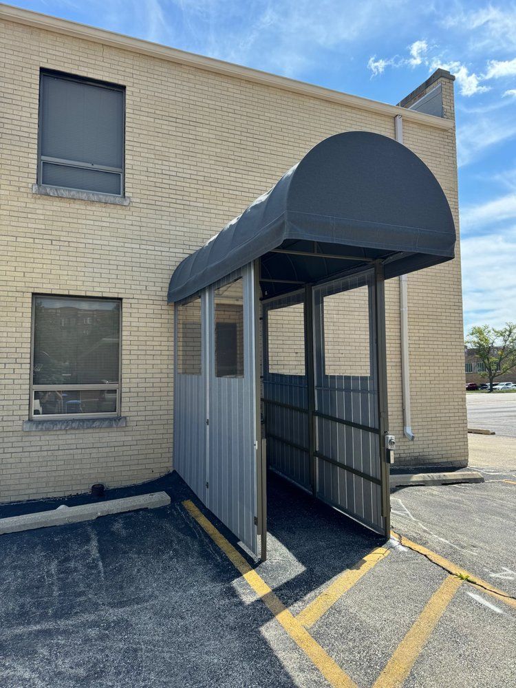 Exterior view of a building with a gray metal and canvas covered entrance.