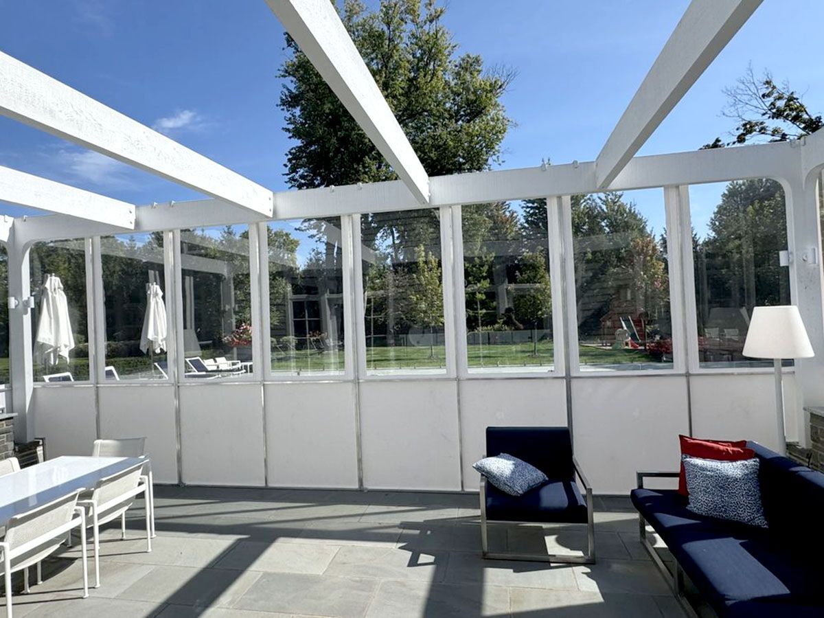 Sunroom with white beams and glass windows, furnished with blue seating and a table