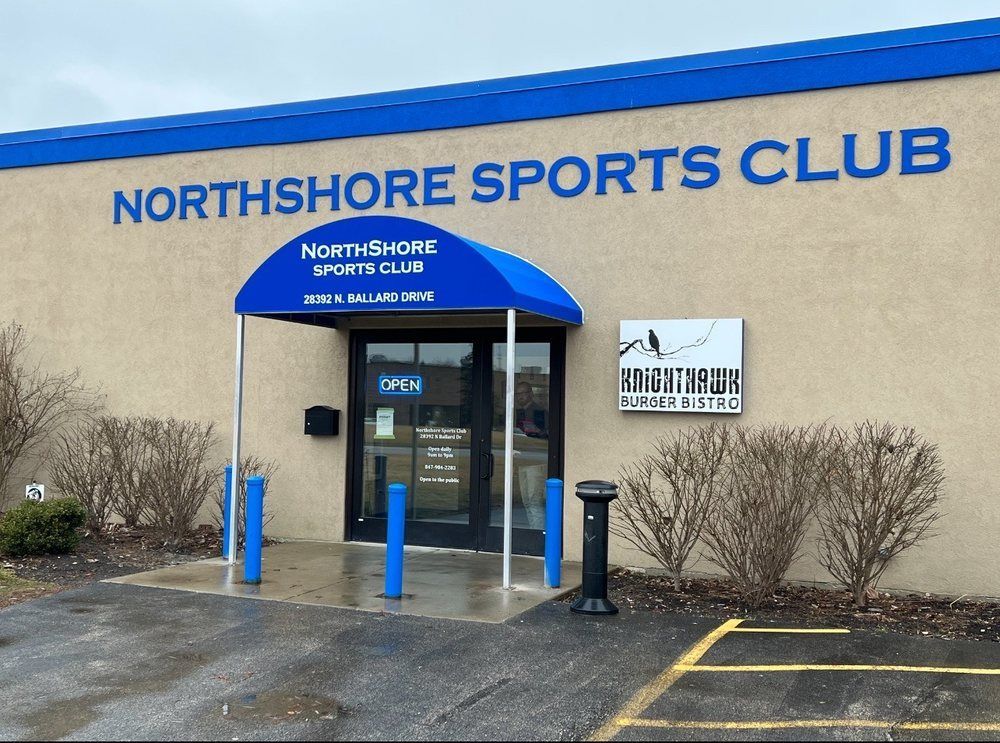 Exterior of Northshore Sports Club, tan building with blue trim and entrance awning.