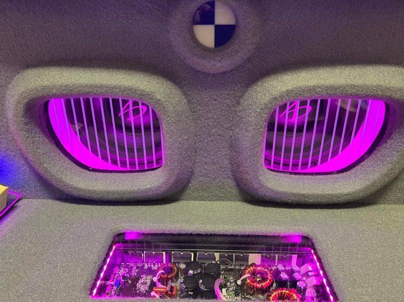 A bmw logo is on the ceiling of a car with purple lights.