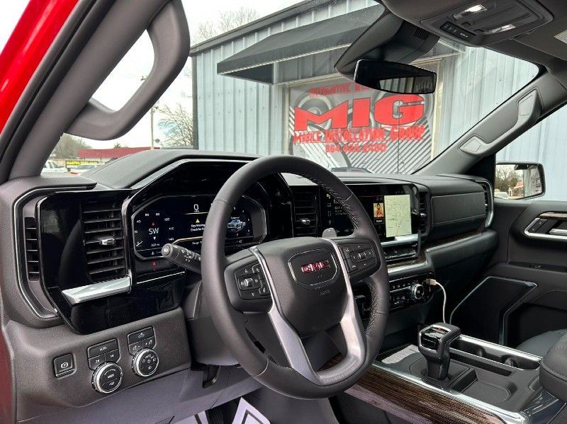 A red gmc truck is parked in front of a building.