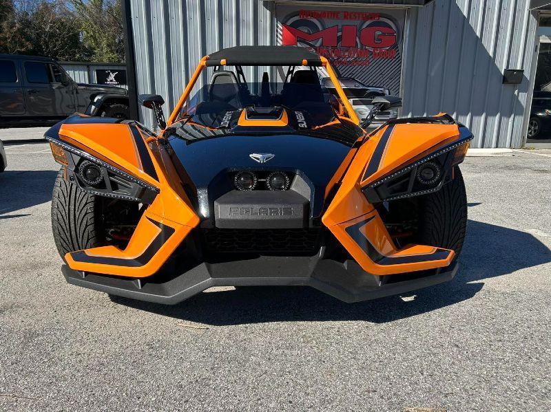 A polaris slingshot is parked in front of a building.