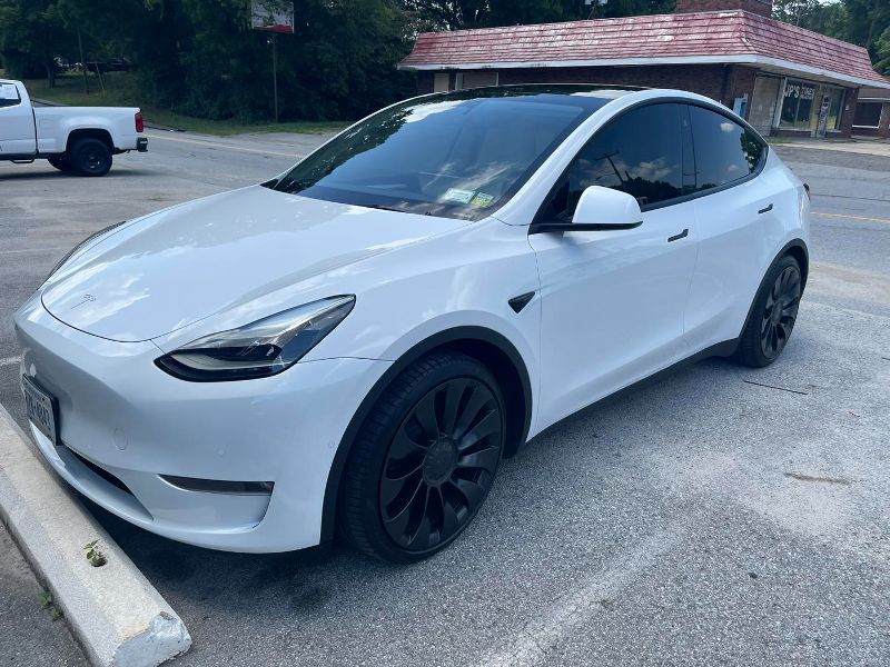 A white tesla model y is parked in a parking lot.