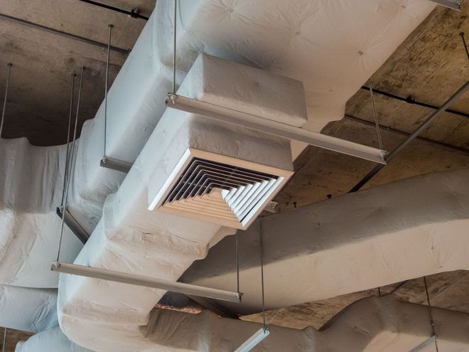 Overhead view of HVAC ductwork with vent and supports, all painted white.