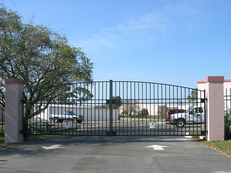 A metal gate is open to a parking lot