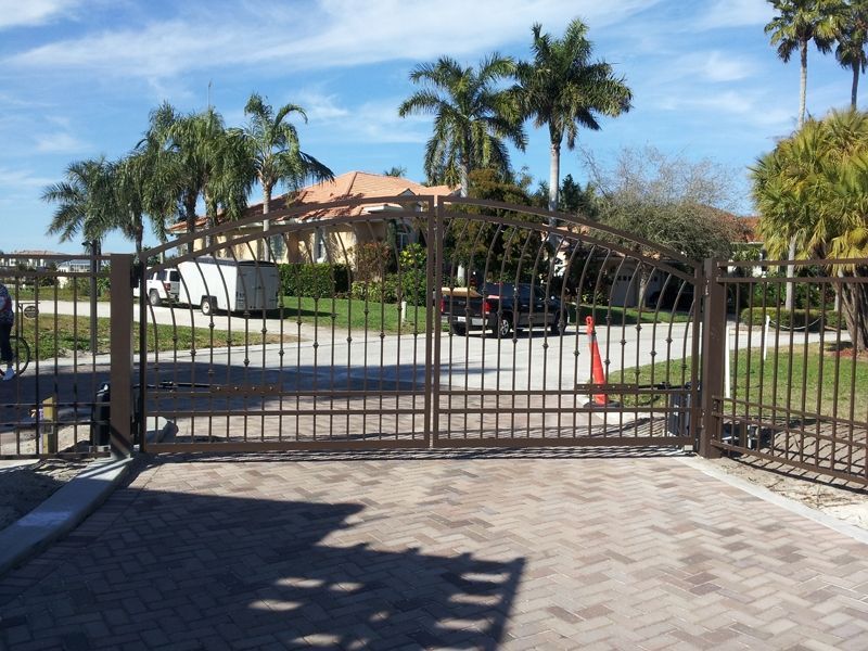 A wrought iron gate is open in front of a house